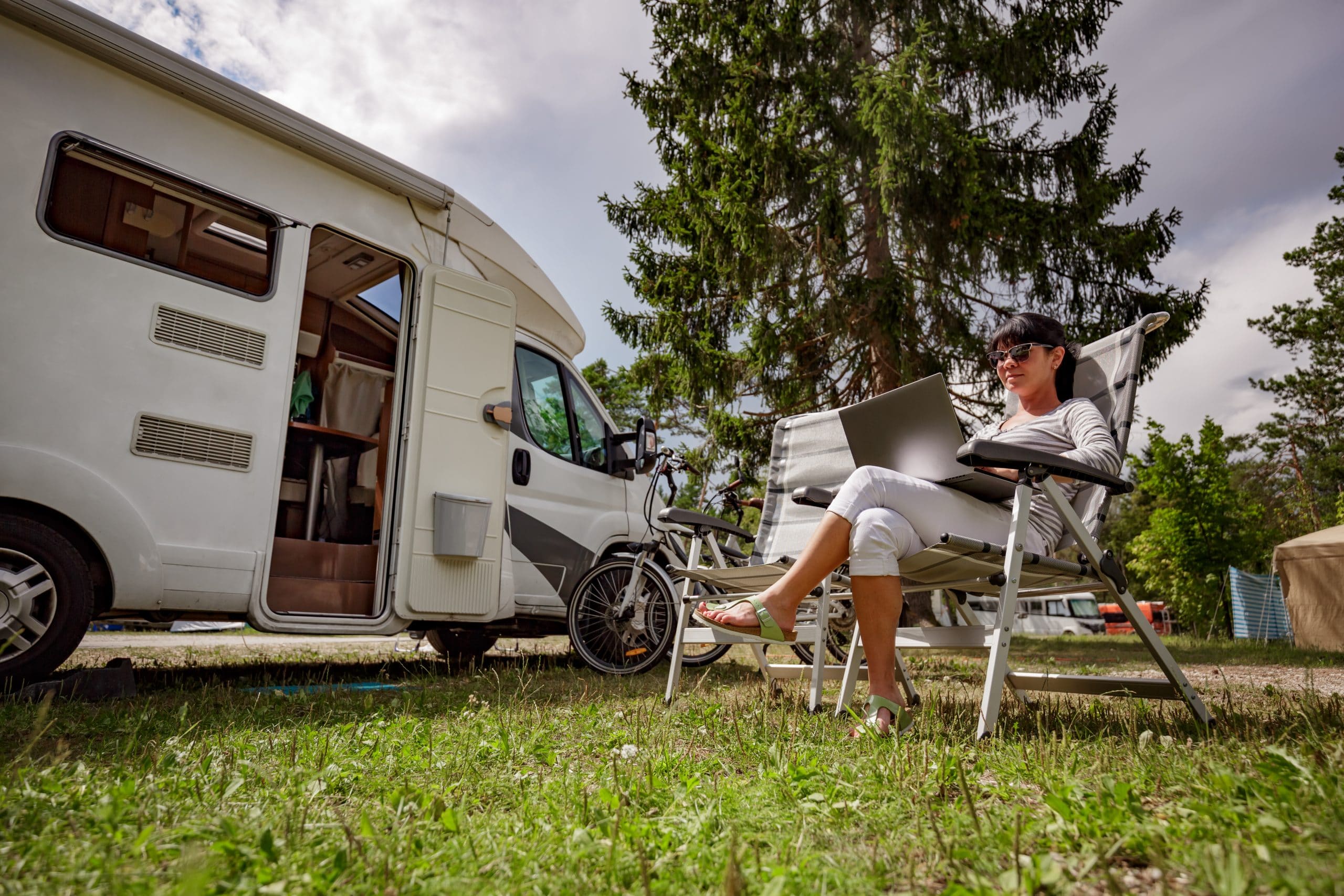 Wifi marketing Woman looking at the laptop near the camping . Caravan car Vacation. Family vacation travel, holiday trip in motorhome RV. Wi-fi connection information communication technology.
